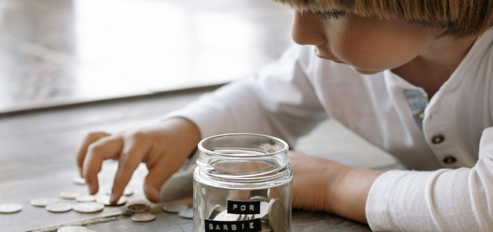 A close up of a child counting coins into a glass jar