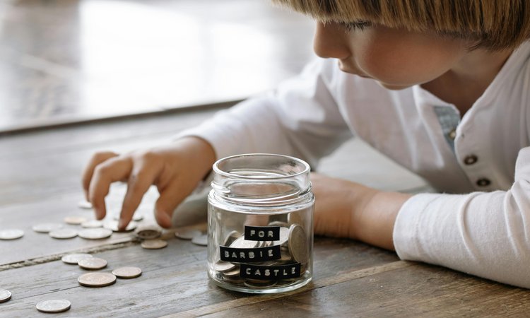 A close up of a child counting coins into a glass jar
