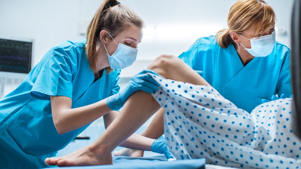 a midwife and obstetrician help a woman give birth vaginally