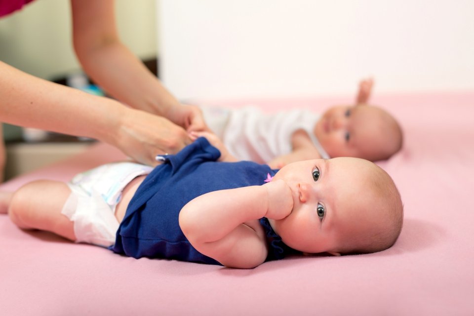 close up of twin babies being changed into new clothes