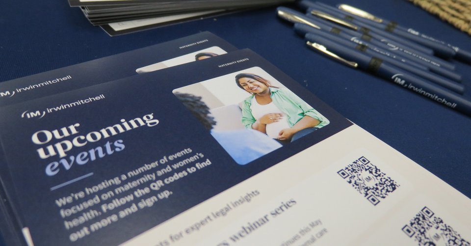 A pile of leaflets and row of pens set out on a blue table