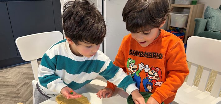 Twin boys stand at a table baking