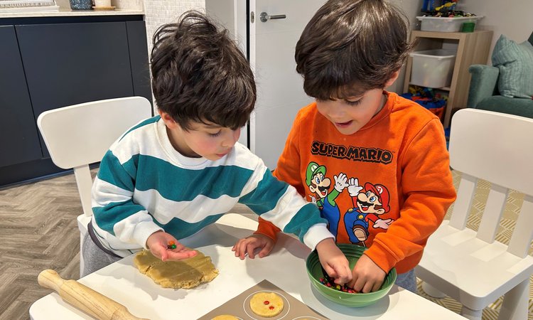 Twin boys stand at a table baking
