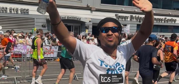 A man turns to wave at the camera whilst running in the London Marathon