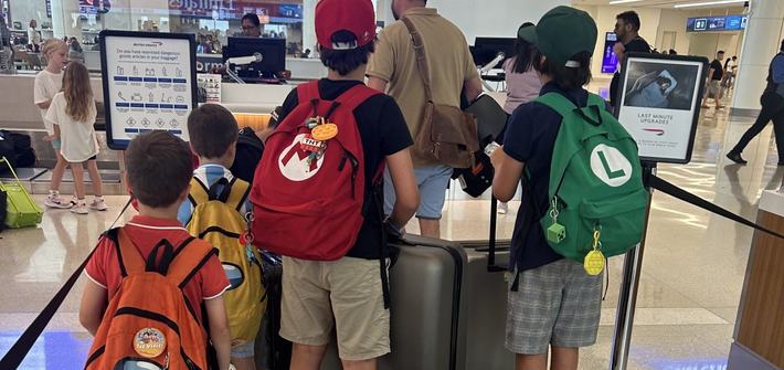 five young children and a man waiting to check-in at the airport