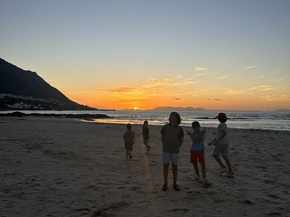 five young children on a beach during sunset