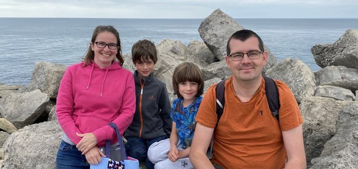 a mother and father with their twin boys at a rocky shore