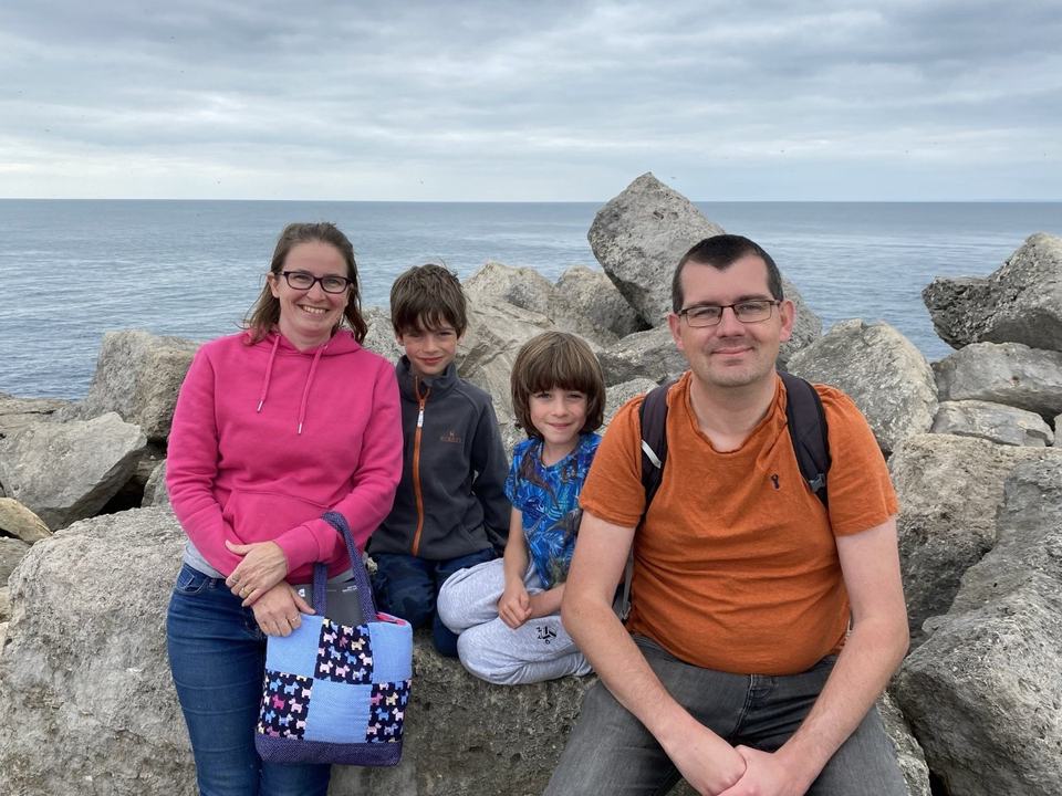 a mother and father with their twin boys at a rocky shore