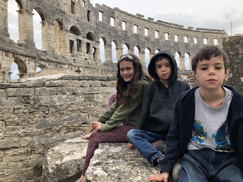 a girl and two boys wearing hearing aids at an amphitheater ruins
