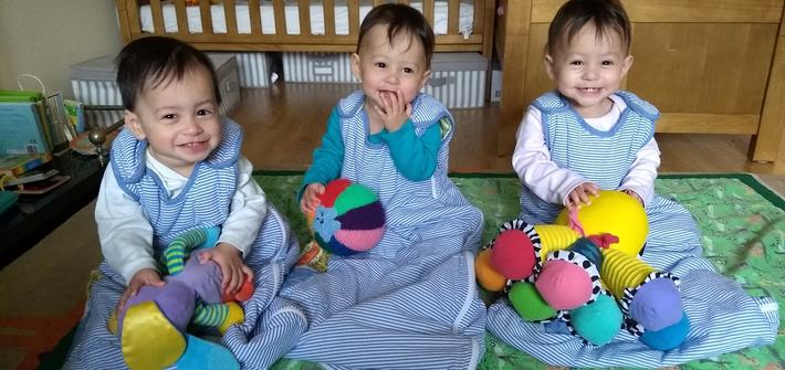 triplet babies in baby sleeping bags in a bedroom