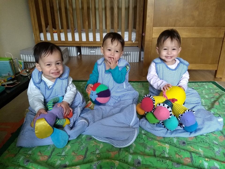 triplet babies in baby sleeping bags in a bedroom