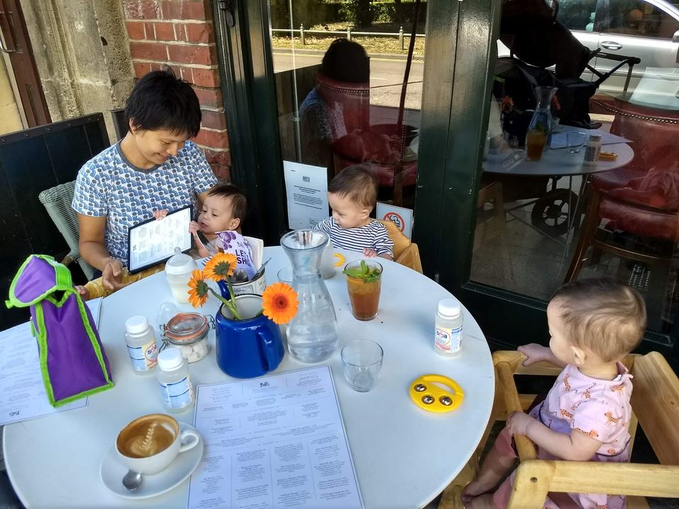 a mother with her triplet babies sat at a table in a restaurant