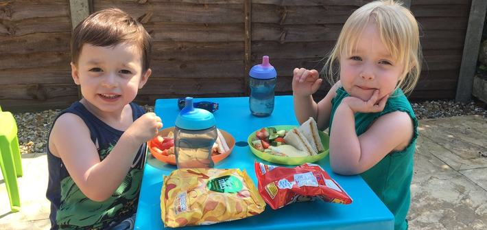 a boy and a girl having lunch on a children's garden table