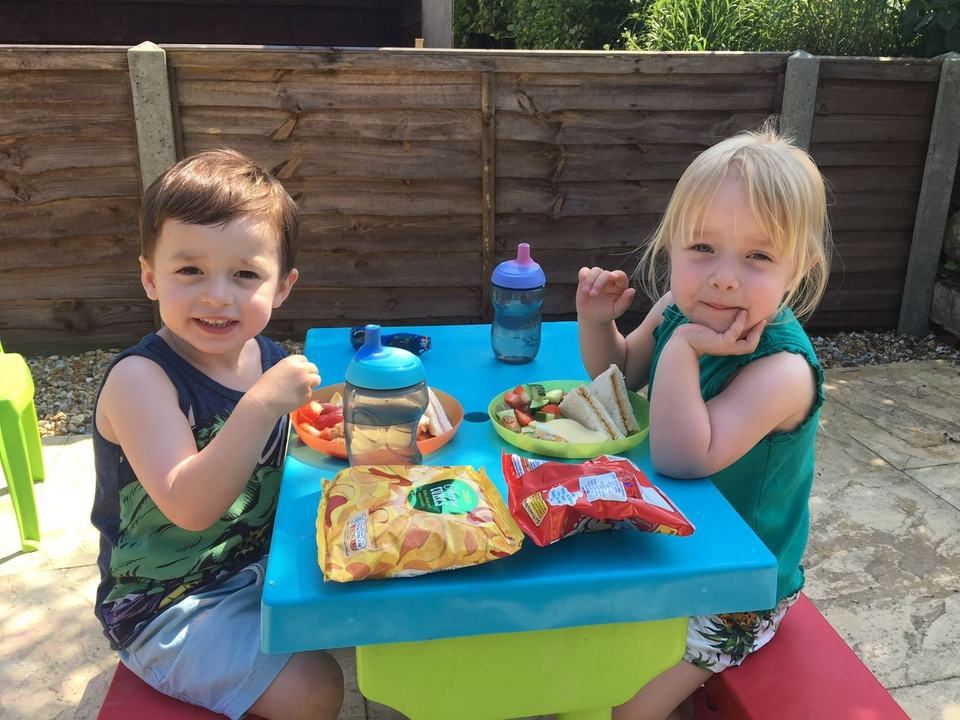 a boy and a girl having lunch on a children's garden table