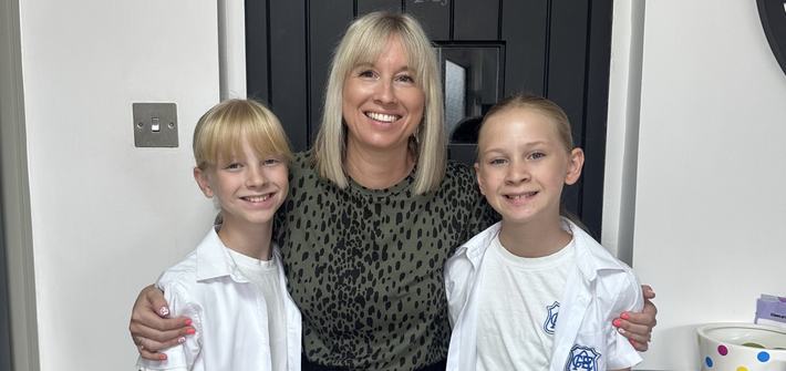 a mother and two twin girls in school uniform smiling