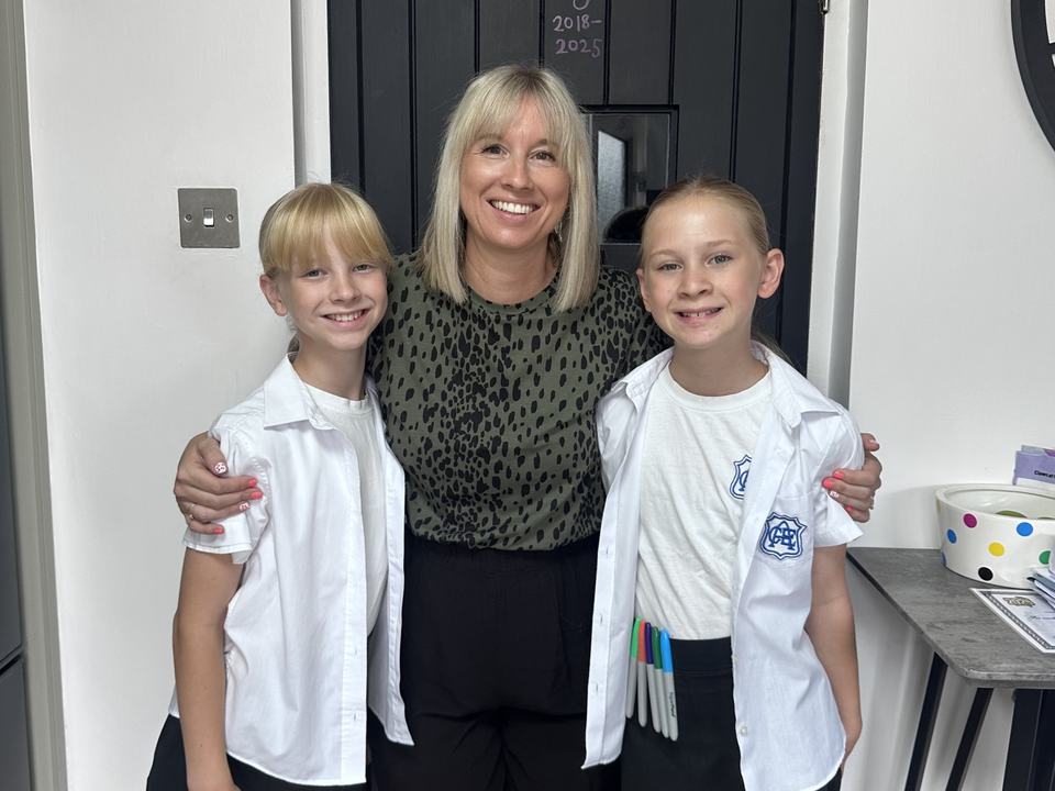 a mother and two twin girls in school uniform smiling