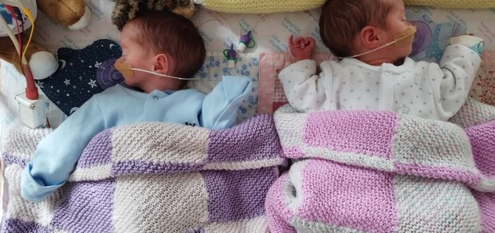 two twin babies sleeping with a feeding tube attached to their noses