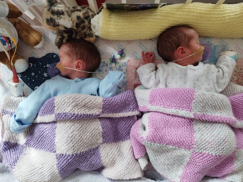 two twin babies sleeping with a feeding tube attached to their noses