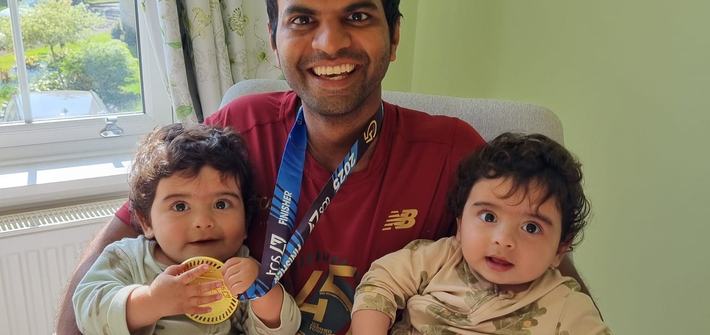 a man wearing a runners' medal holding twin babies