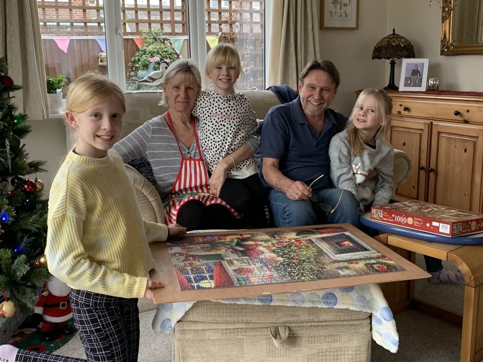 grandparents with three grandchildren completing a 1000 piece jigsaw puzzle