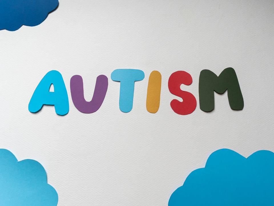 paper cutouts spelling autism on a white surface