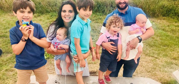 a mother and father with their twin boys, a toddler and twin babies in a park