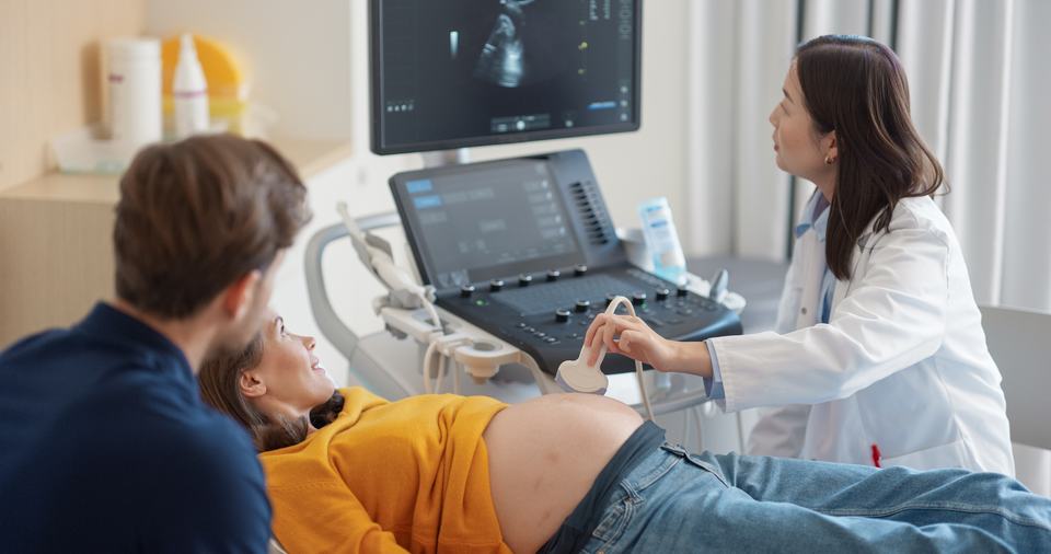 an Asian doctor performing sonography on a pregnant woman