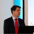 A man in a suit standing at a lectern speaking