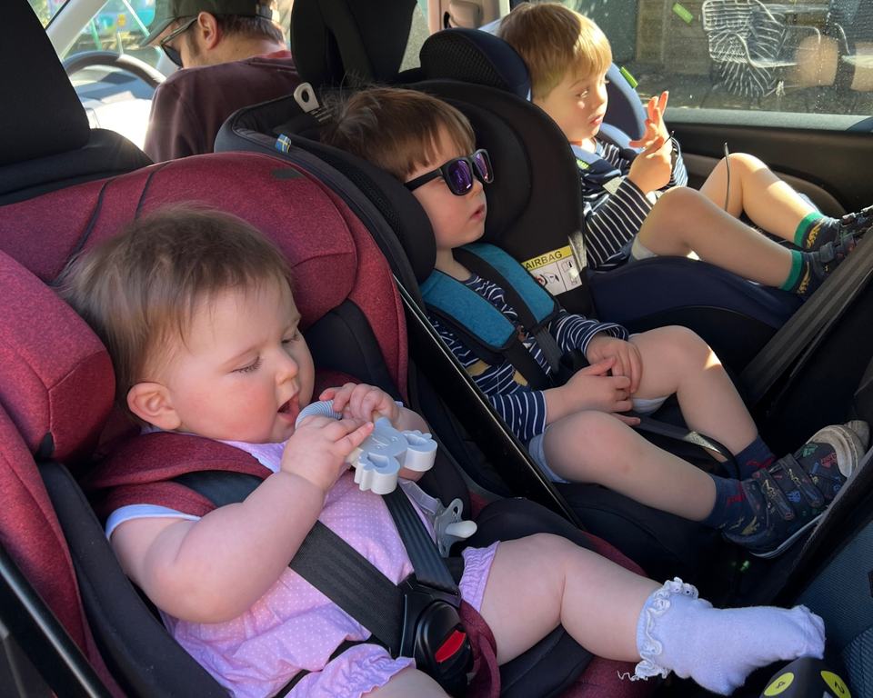 two twin toddlers and a baby sat in rear facing car seats in a car