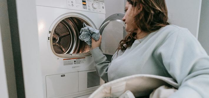A woman loads clothes into a washing machine