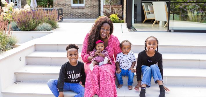a mother and her four children smiling, sat on steps in the back garden