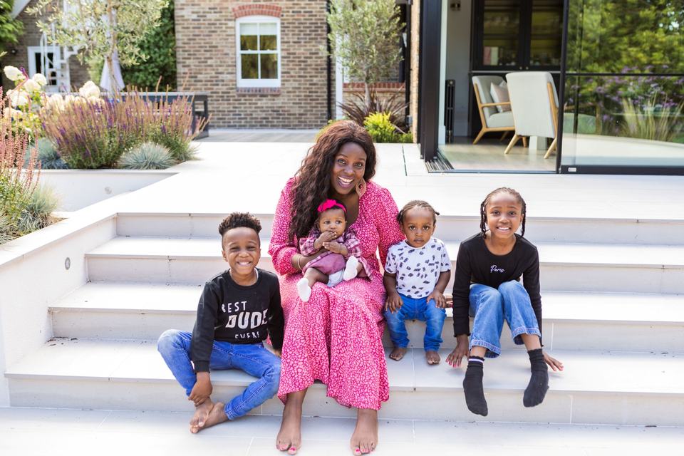 a mother and her four children smiling, sat on steps in the back garden