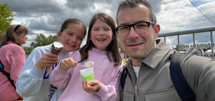 a father with his twin girls eating ice cream in a park