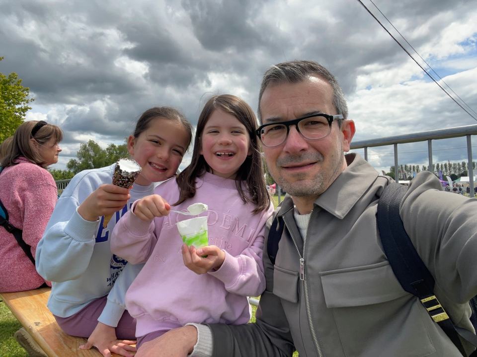 a father with his twin girls eating ice cream in a park
