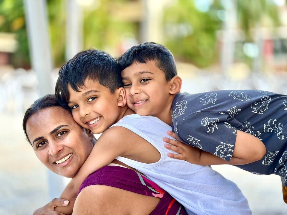 a mother with her twin boys hugging and leaning on her back