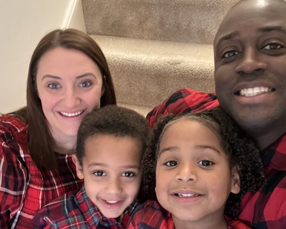 a selfie photo of a mother and father with their twin children wearing red pyjamas