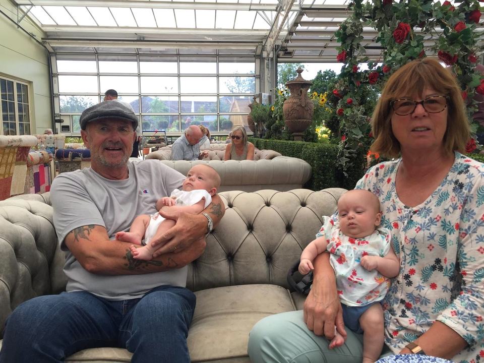 two grandparents each holding a twin baby in a garden centre