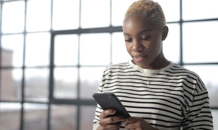 A woman stands looking down at her smartphone