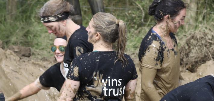 A group of woman stand covered in mud