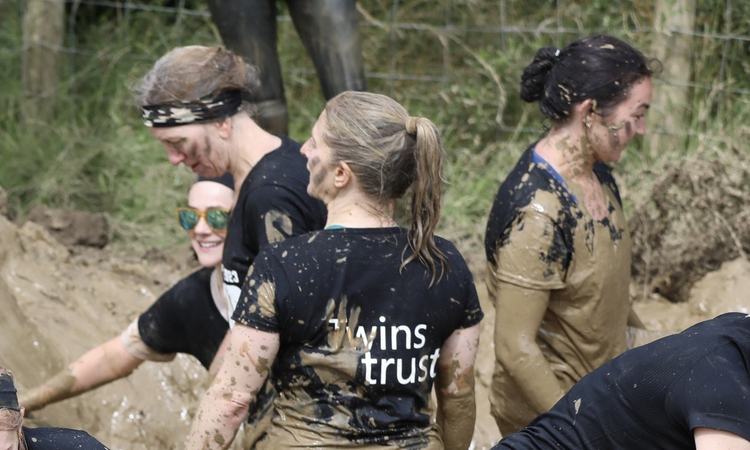 A group of woman stand covered in mud