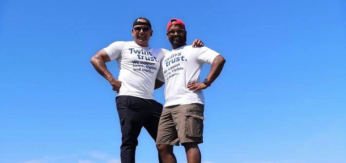 Two men stand arm in arm on a tree stump