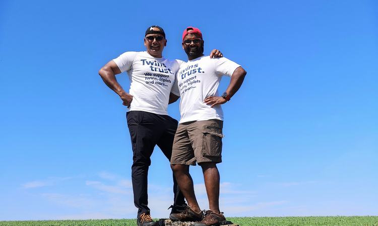 Two men stand arm in arm on a tree stump