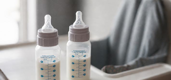 Two baby bottles sit on an empty high chair