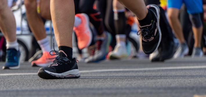 close up of a runners feet running amongst other marathon runners