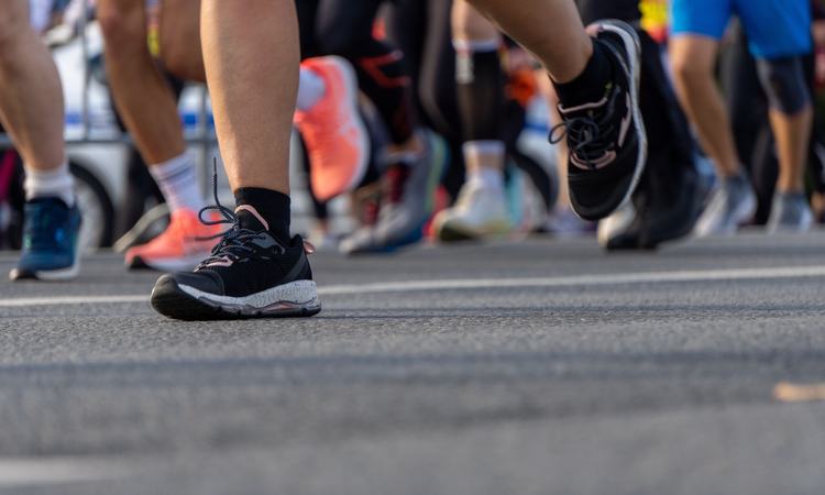 close up of a runners feet running amongst other marathon runners