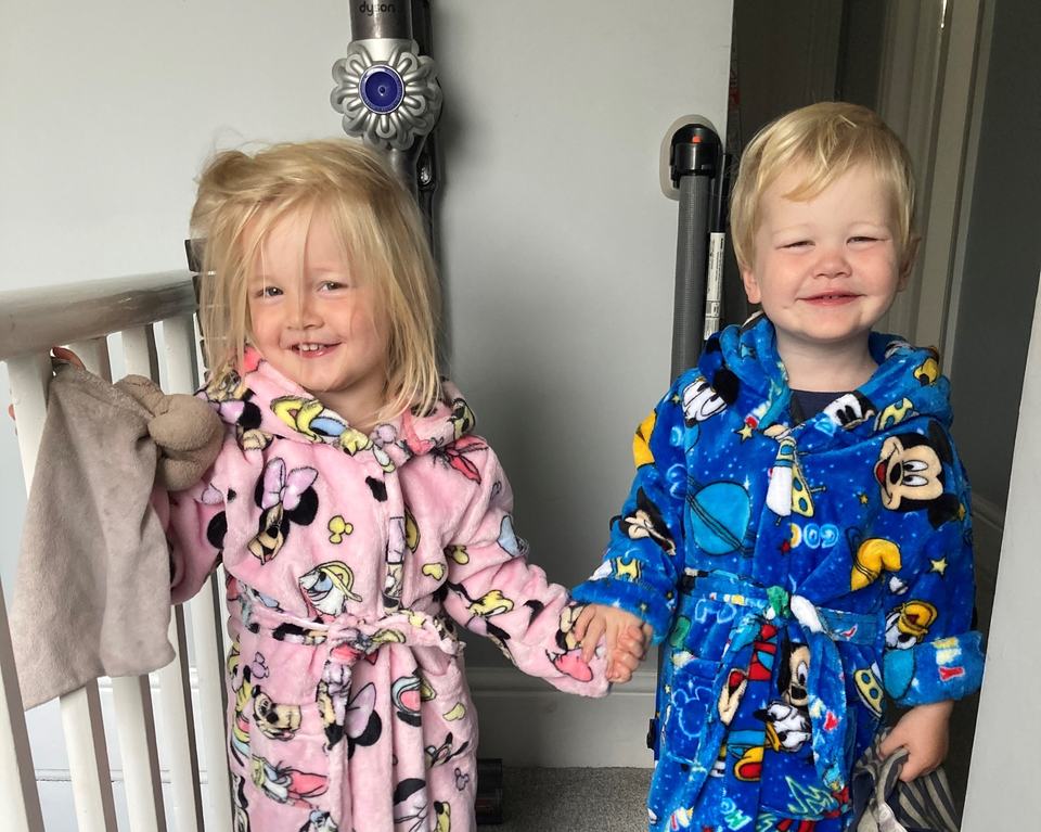 twin brother and sister in their bathrobes holding hands