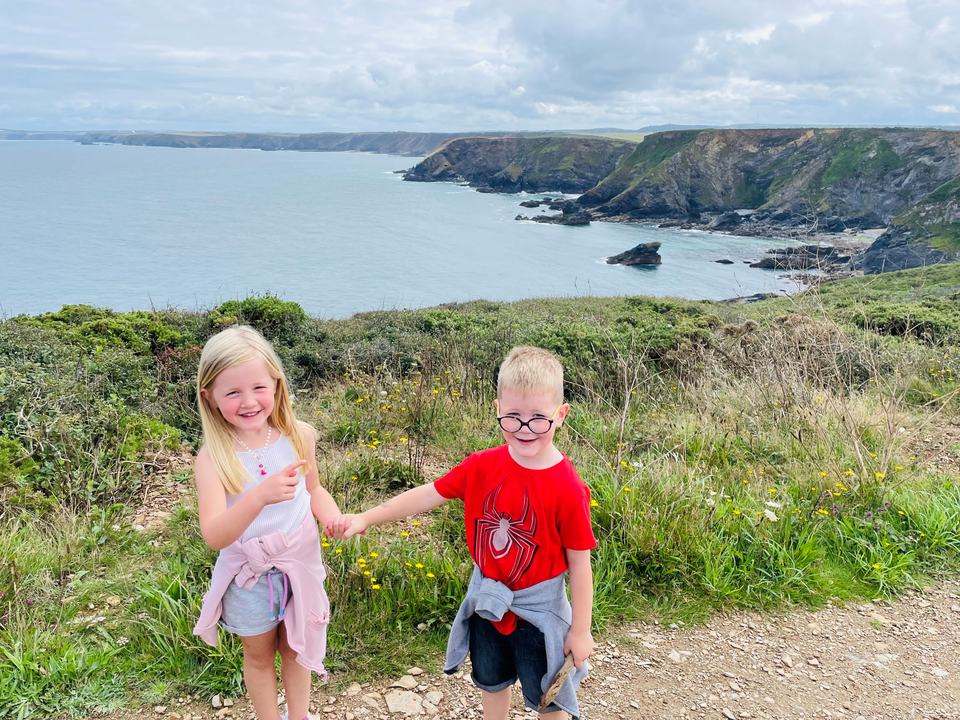 twin brother and sister holding hands walking on a trail