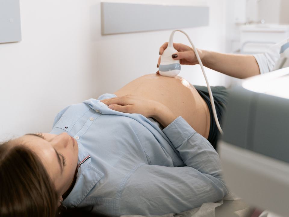 Pregnant woman receiving ultrasound scan in clinic setting