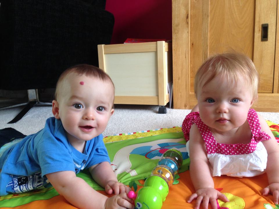 twin babies playing on a single play mat