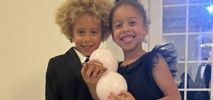 two twin children smiling holding a balloon at a party